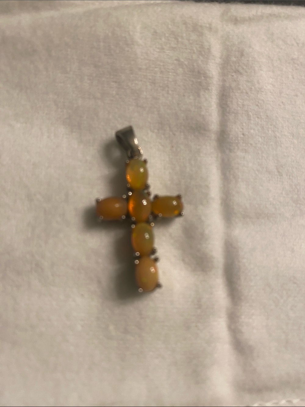 a sterling silver cross pendant featuring five prong-set oval orange fire Opals
